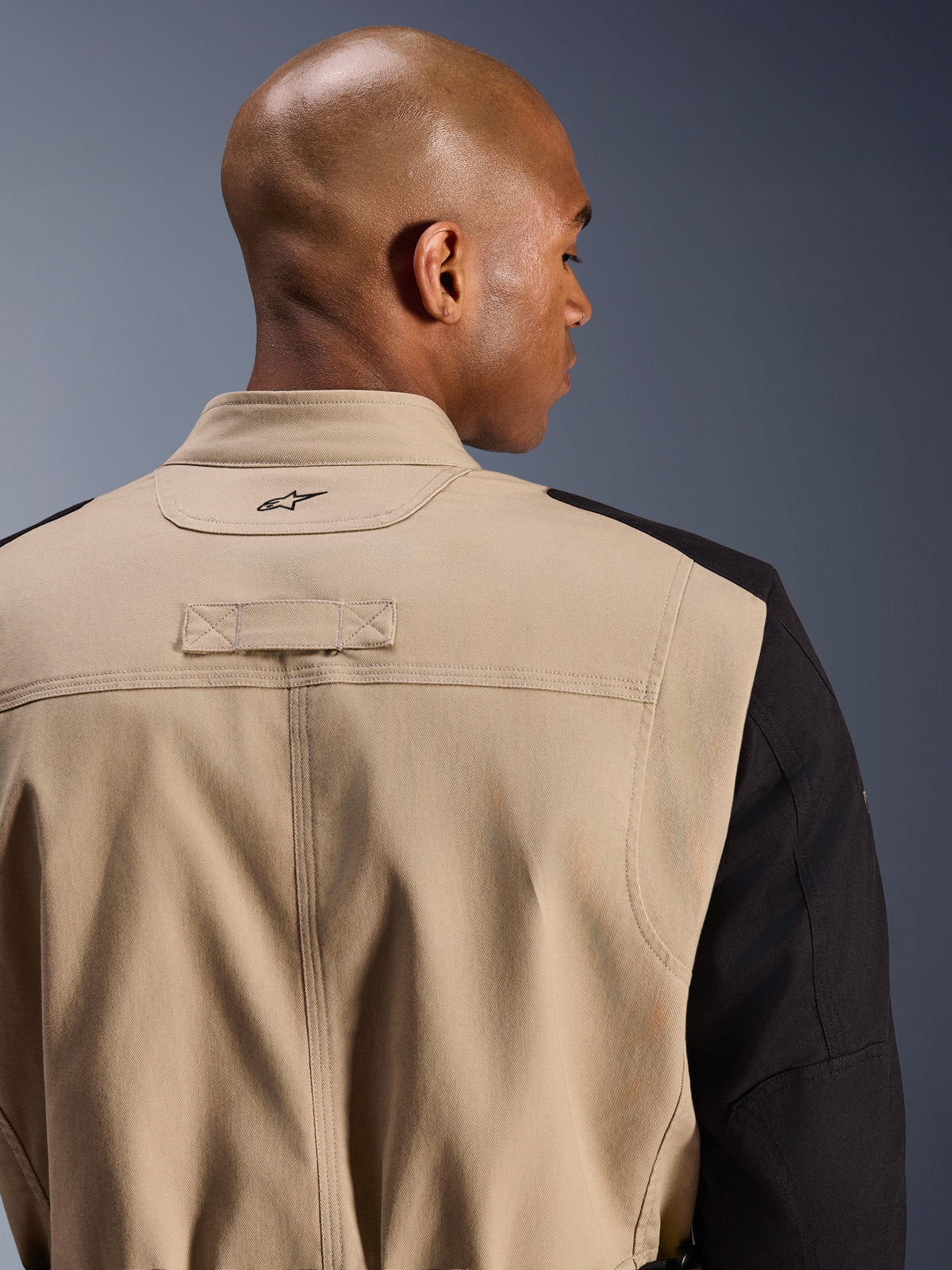 Alpinestars Dice Jacke, urbane Motorradjacke, Hellbraun und Schwarz, Detailansicht des Rückenkragens und der Schulter, mit eingesticktem Logo, robuste Polycotton-Twill-Konstruktion, straßentauglicher Workwear-Stil