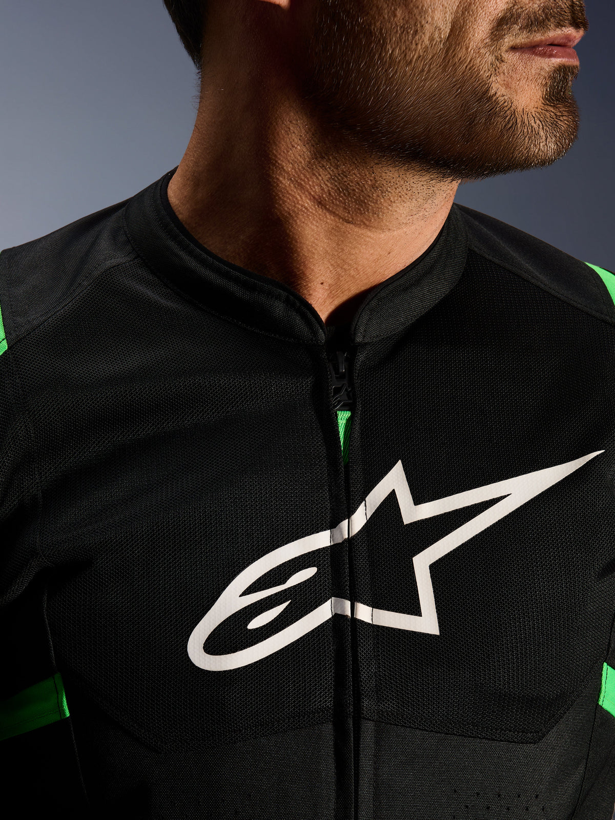 Close-up of Alpinestars T-SPS Air V2 Jacket, Black and Fluo Green, featuring breathable tech mesh panels, central zipper, and prominent white Alpinestars star logo on the chest, performance motorcycle gear