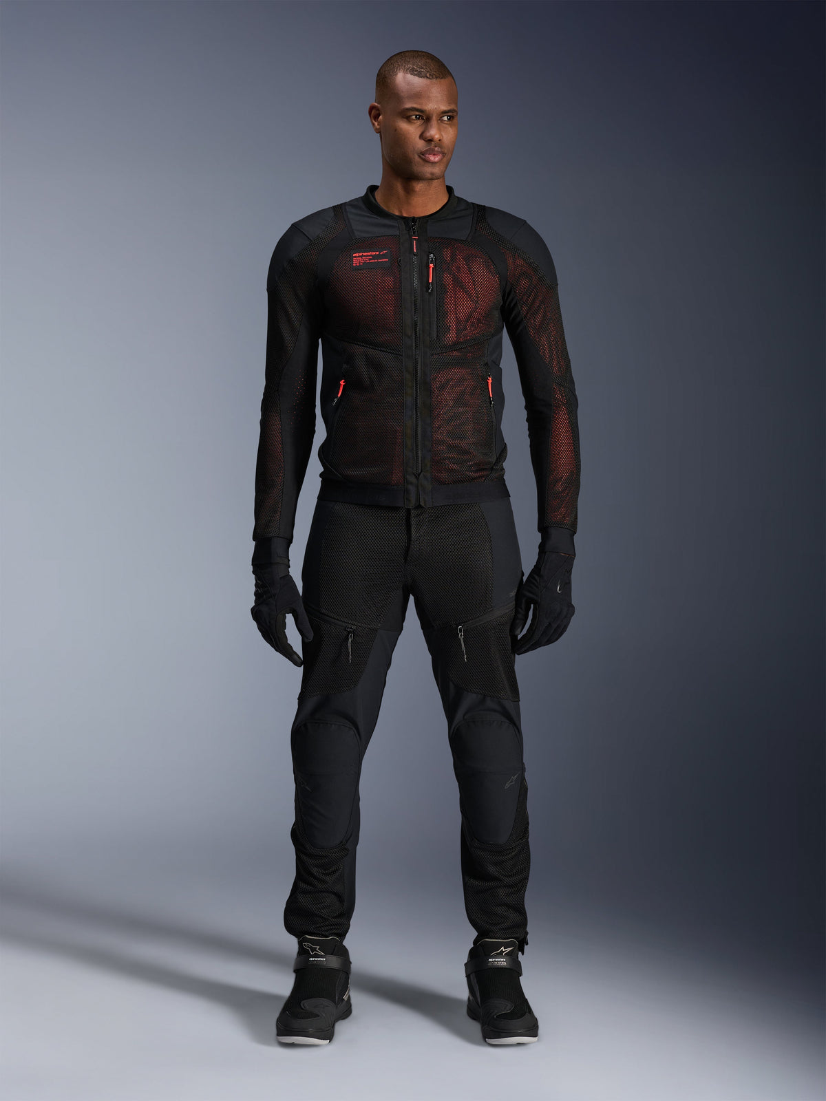 Alpinestars Troop-Air Pro Jacket, technische gepantserde luchtjas, Zwart en Red Fluo, gedragen door een mannelijk model met bijpassende motorbroek en handschoenen, voorzien van high-flow mesh-panelen en rode accenten, urban motorkleding