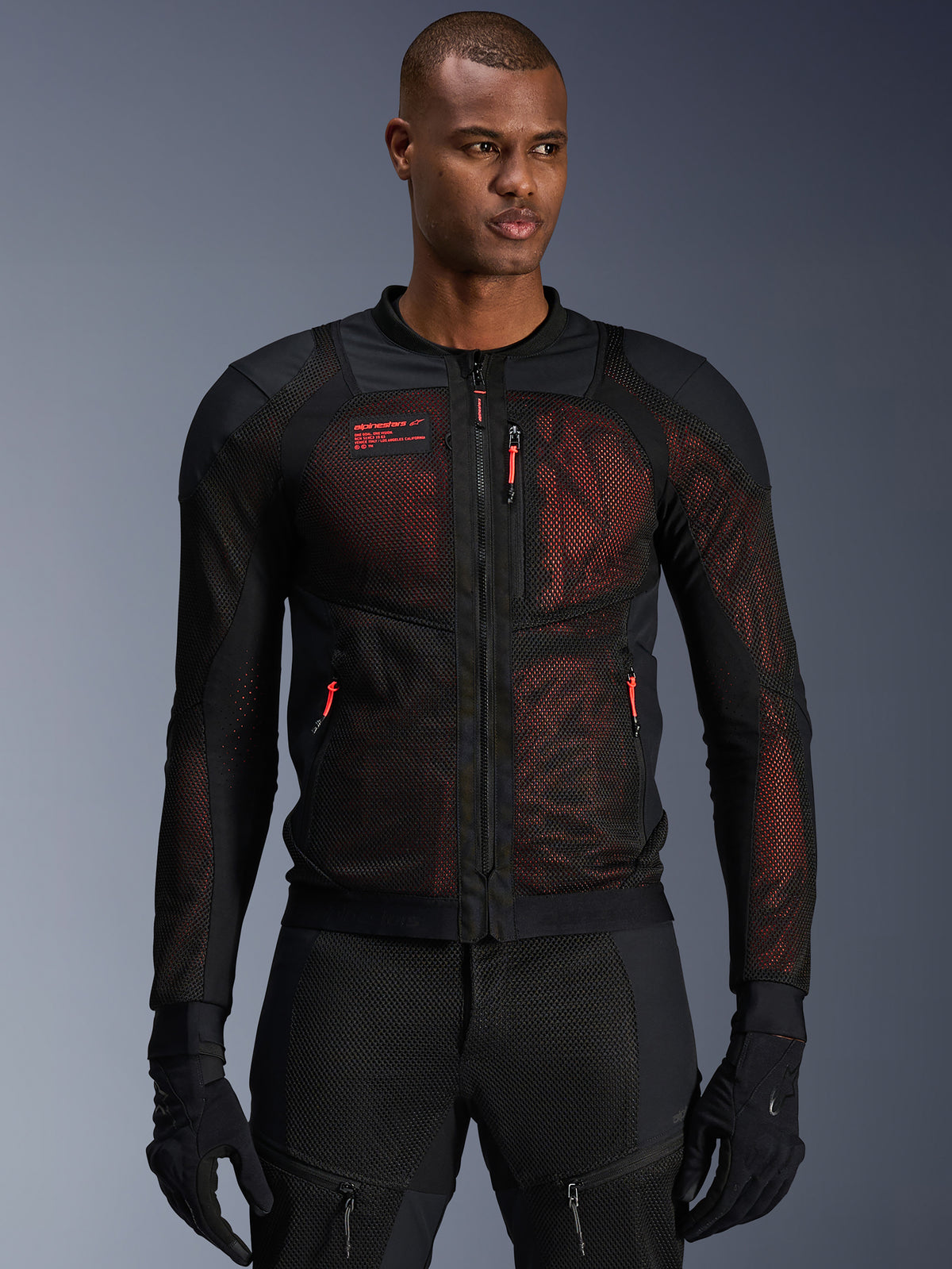Alpinestars Troop-Air Pro Jacket, technische gepantserde motorjas, zwart en fluo rood, met rode ritstrekkers en Alpinestars-logo, ademende mesh-panelen met rode onderlaag, gedragen met bijpassende zwarte motorbroek en handschoenen