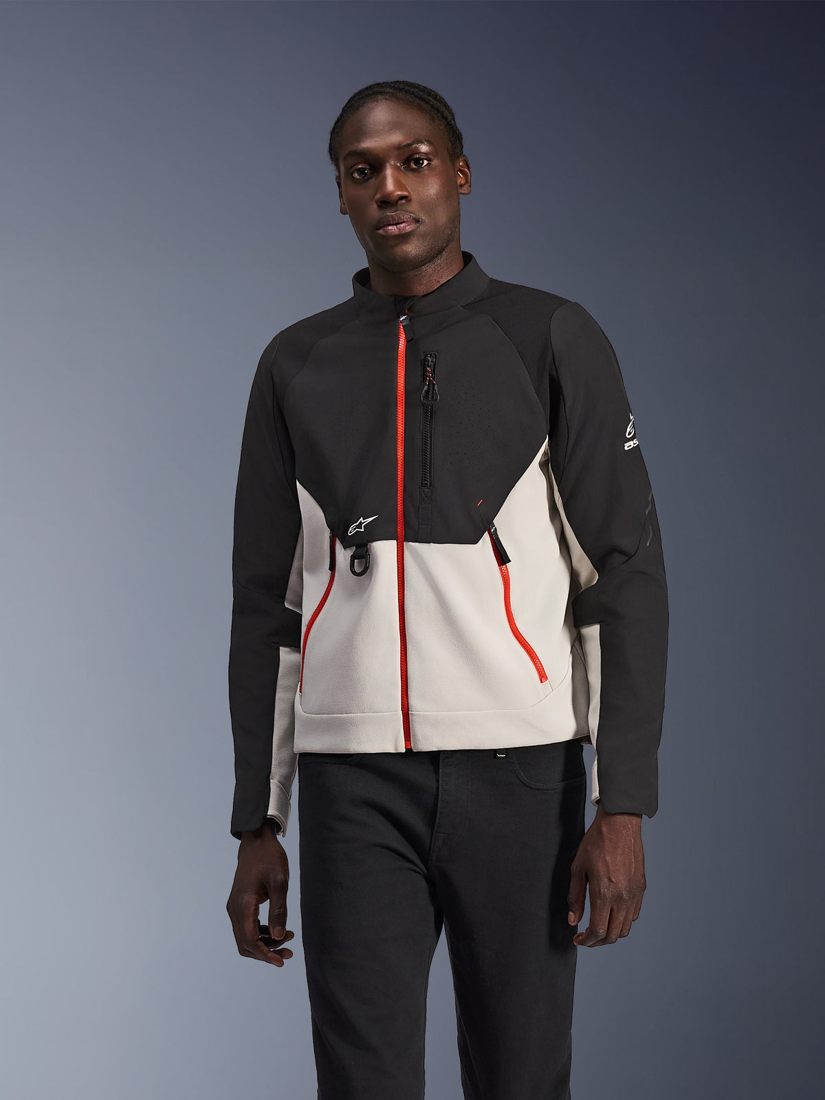 Alpinestars Provoke Jacket, stedelijke motorjas, zwart en lichtgrijs met opvallende rode ritsen, hoge kraag, voorzien van logo-details op de borst en mouw, modern beschermend straatklaar ontwerp gedragen door model