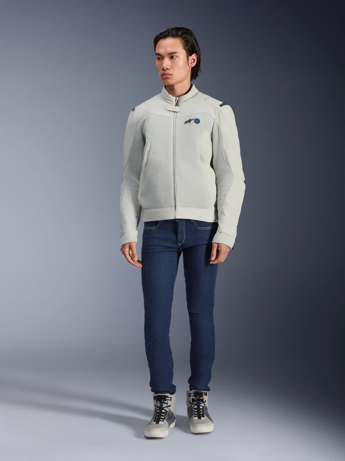 Alpinestars Circal-1 Air Jacke, Metallgrau, urbane Motorradjacke mit Mesh-Belüftungseinsätzen, getragen von einem Model mit blauen Jeans und grauen Riding-Sneakern, minimalistisches Design für nachhaltiges Fahren in der Stadt.
