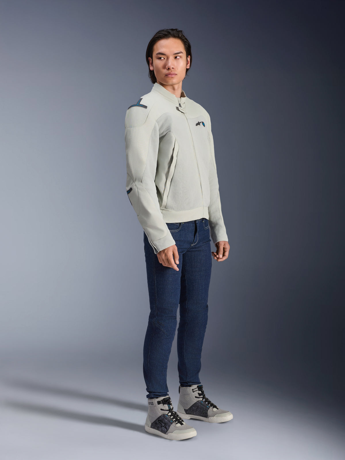 Alpinestars Circal-1 Air Jacke in Metal-Grau und Methyl-Blau, getragen von einem Model mit dunkelblauen Jeans und grauen Sneakern, urbane Sommer-Motorradjacke mit großen Mesh-Einsätzen für Luftzirkulation und minimalistischem Design.