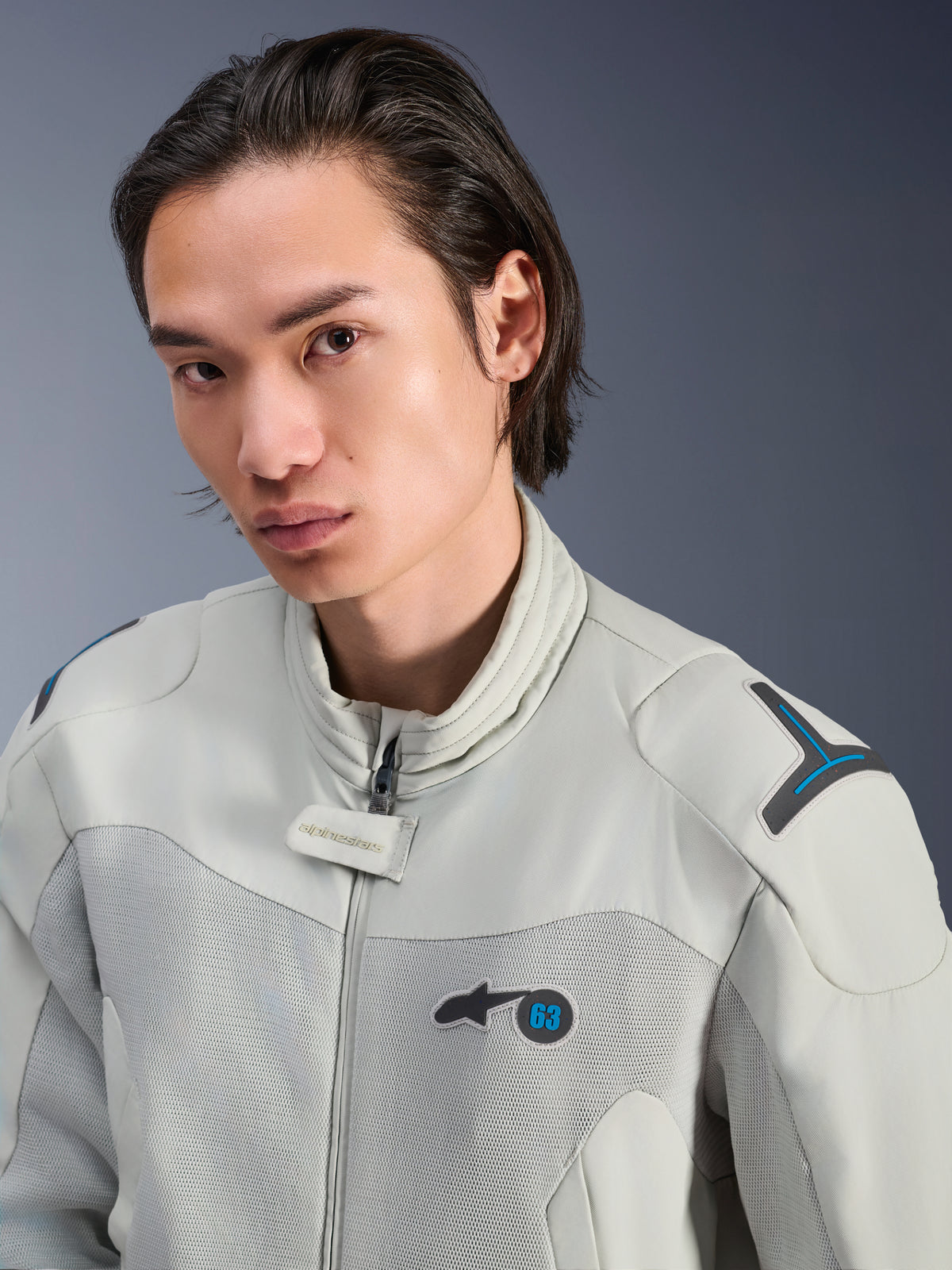 Alpinestars Circal-1 Air Jacke, Metal Gray mit Methyl Blue Akzenten, männliches Modell trägt urbane Sommer-Motorradjacke, Nahaufnahme der Mesh-Belüftungseinsätze und des minimalistischen Brandings auf der Brust
