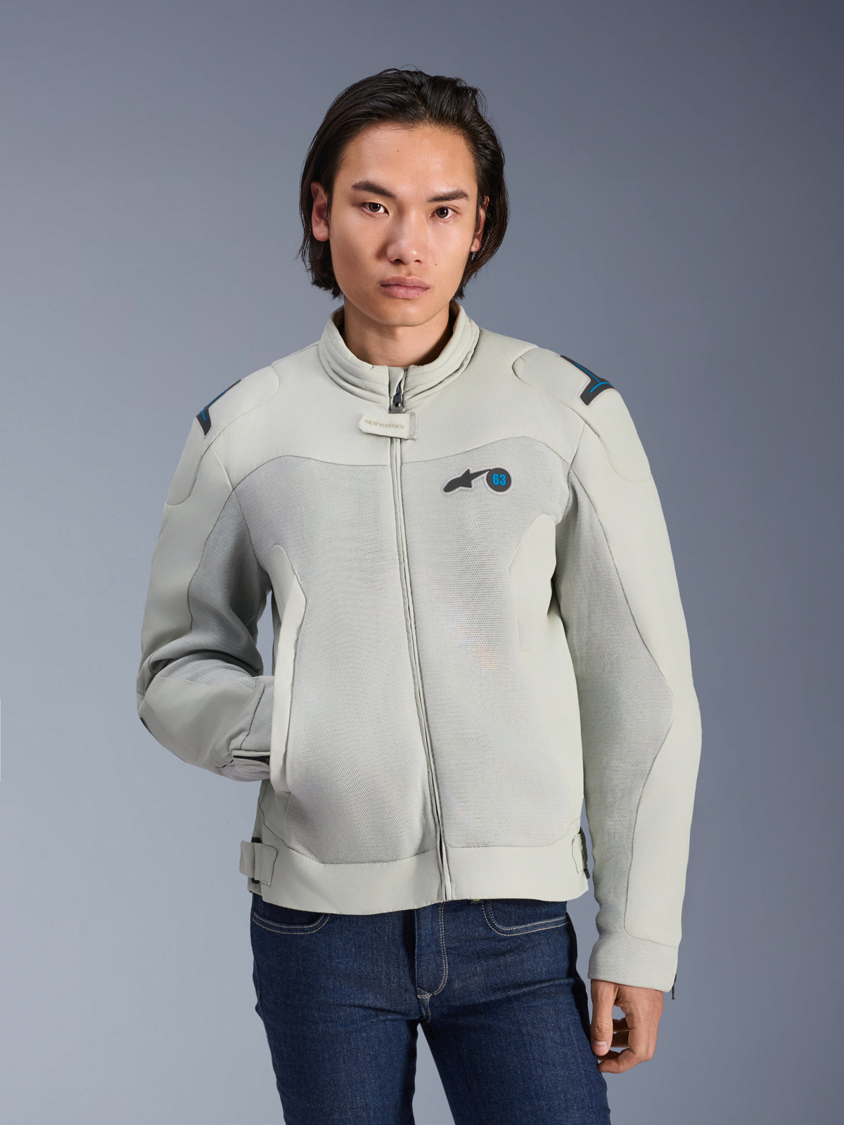 Alpinestars Circal-1 Air Jacke, Metallgrau und Methylblau, urbane Motorradjacke mit Mesh-Belüftungseinsätzen, Frontreißverschluss und gepolstertem Kragen, getragen von einem Model mit blauen Jeans, futuristisches nachhaltiges Design für Sommerfahrten