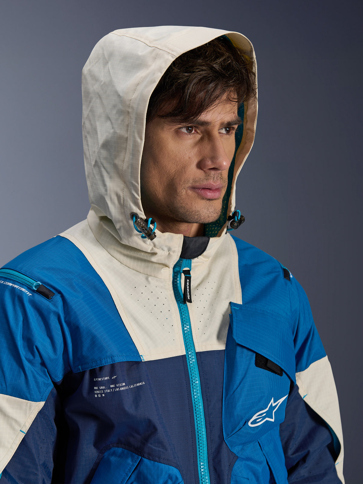 Alpinestars Mogress Air jas, heren-motorjas, blauw en crème, geventileerd textiel, model draagt de capuchon op.