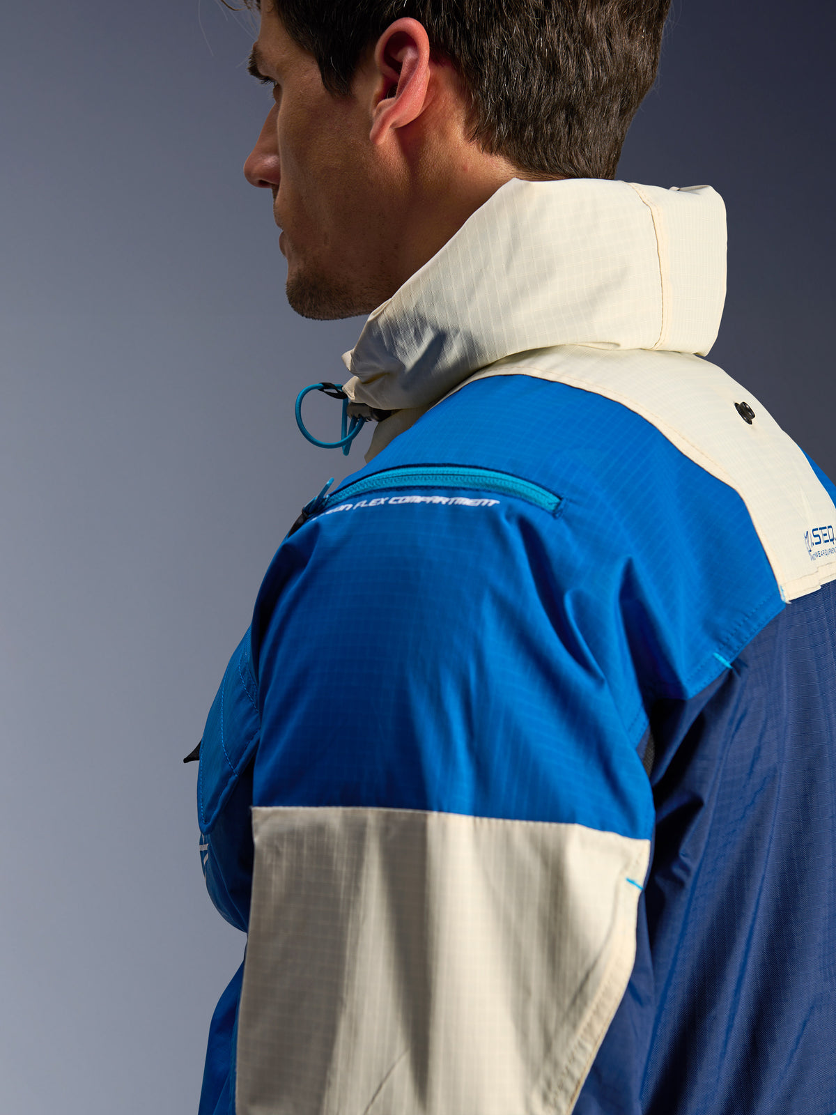 Alpinestars Mogress Air Jas, urban herenmotorjas, blauw en almond, gerecycled ripstop, hoge kraag met capuchon, zijaanzicht.