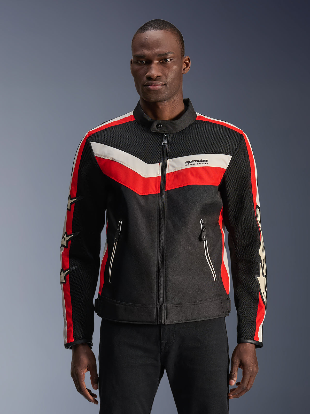 Alpinestars T-Dyno Air Jacke, Schwarz mit leuchtend roten und Ecru-farbenen Chevron-Streifen, Stern-Akzente an den Ärmeln, Hochkragen mit Frontreißverschluss, Reißverschlusstaschen, Vintage-inspiriertes Textil-Motorradjacken-Design