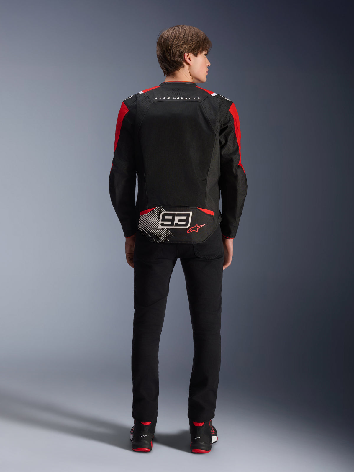 Alpinestars MM93 T-SPS Air V2 Jacke, Rückansicht am Modell, Schwarz mit leuchtend roten und weißen Akzenten, mit Marc Marquez Signature-Branding und 93-Logo auf dem Rücken, Performance-Textil-Motorradjacke für urbanes Fahren.