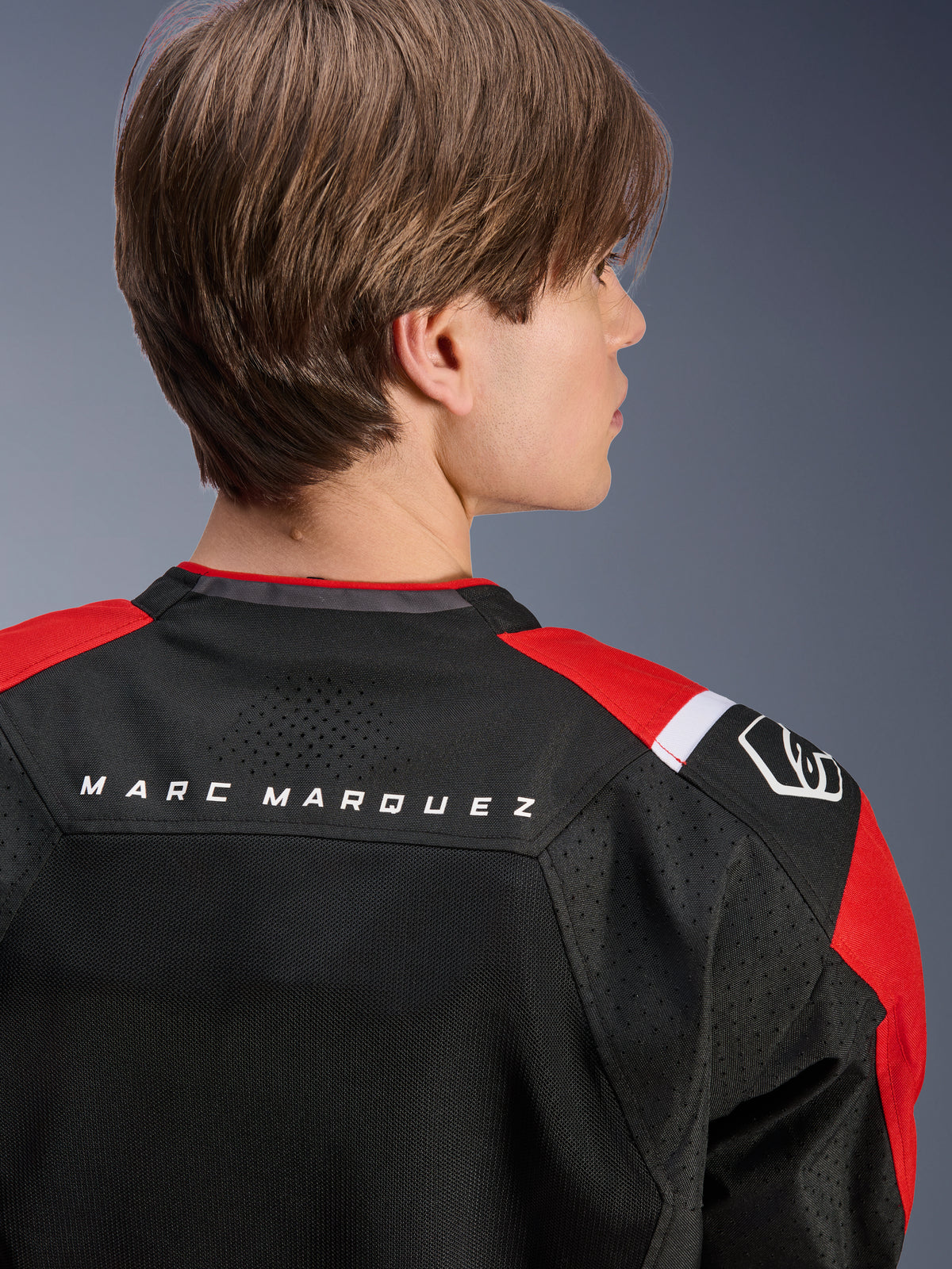 Alpinestars MM93 T-SPS Air V2 Jacke, Rückansicht des oberen Rückens und der Schultern, Schwarz mit leuchtend roten und weißen Details, „MARC MARQUEZ“-Schriftzug über der Schulterpasse, mit technischen Mesh-Einsätzen und Schulterlogo, urbane Sport-Motorradbekleidung