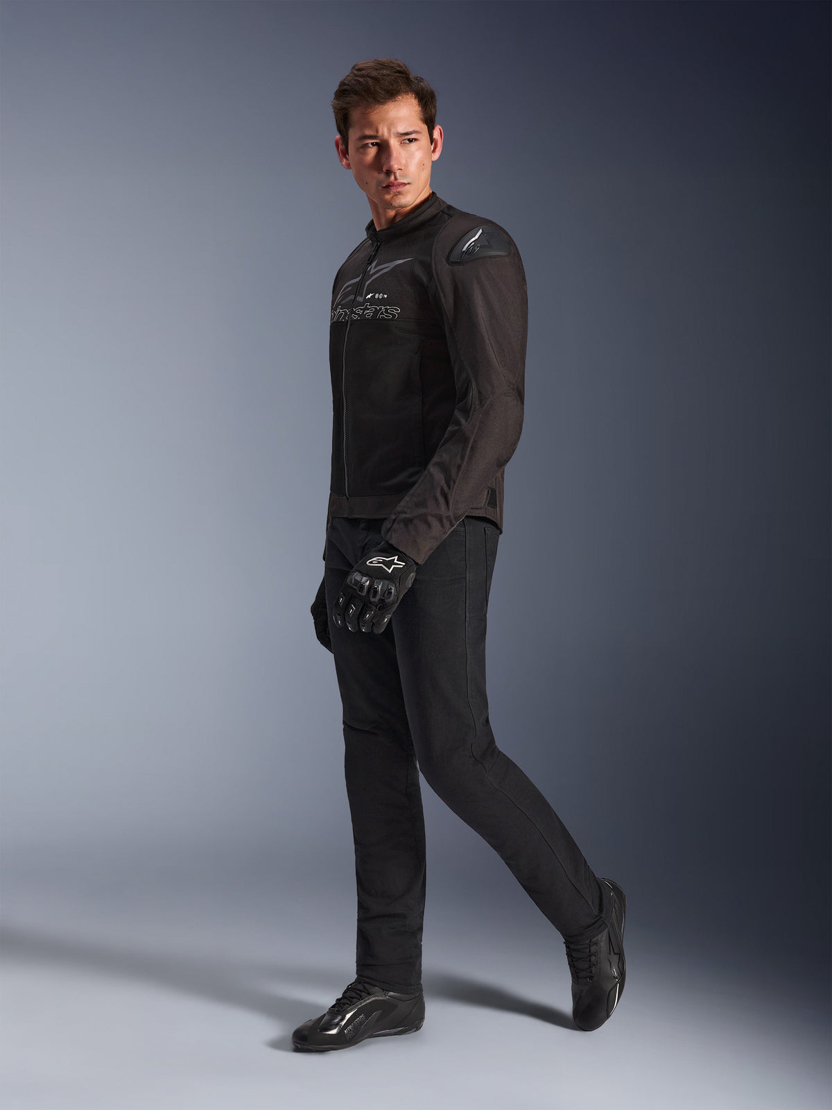 Alpinestars SMX Air Jas in Black Anthracite, gedragen door model met bijpassende zwarte motorbroek, handschoenen en schoenen, studio-opname van het volledige lichaam, sportieve motoruitrusting met tech mesh en schoudersliders