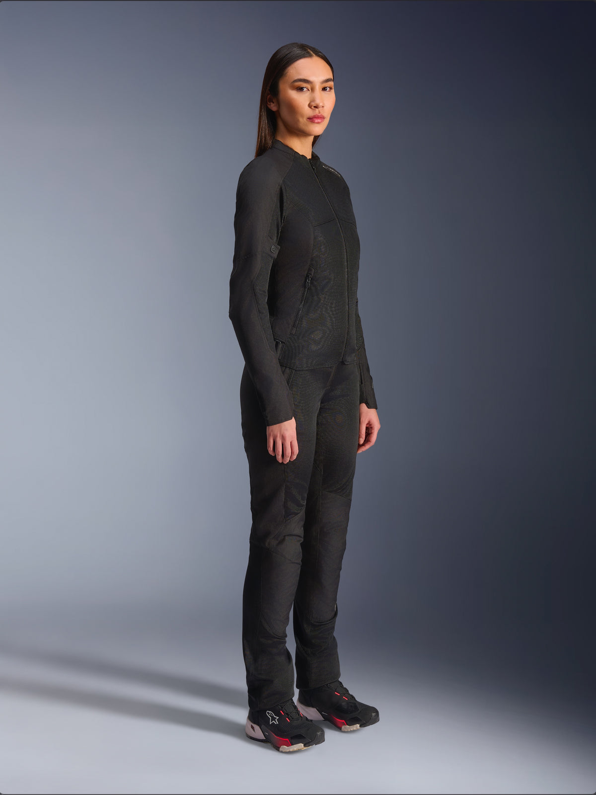 Alpinestars Stella C-1 Air Damenjacke in Schwarz, Textil-Motorradjacke mit Mesh-Einsätzen, kombiniert mit passender schwarzer Fahrhose und technischen Sneakern, Studioaufnahme eines kompletten urbanen Motorrad-Outfits.