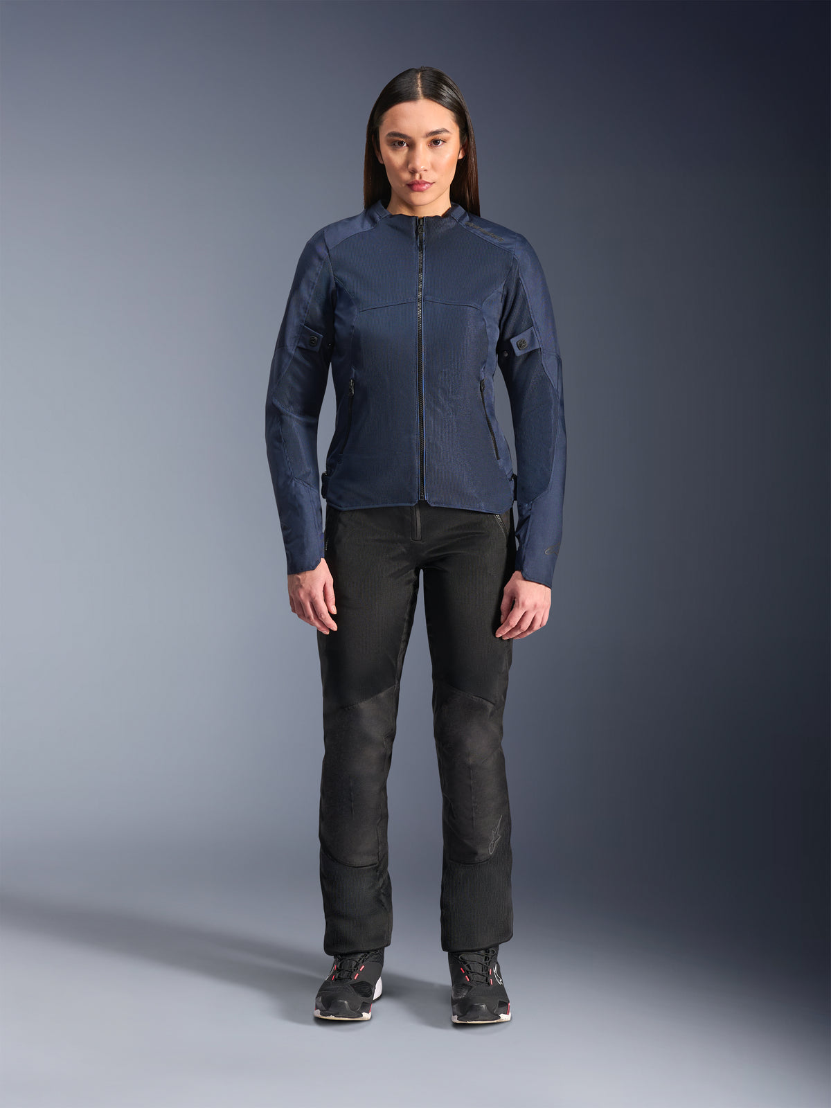 Woman model wearing Alpinestars Stella C-1 Air Jacket in Blue, urban motorcycle jacket with tech mesh panels, paired with black riding pants and black sneakers, studio front view
