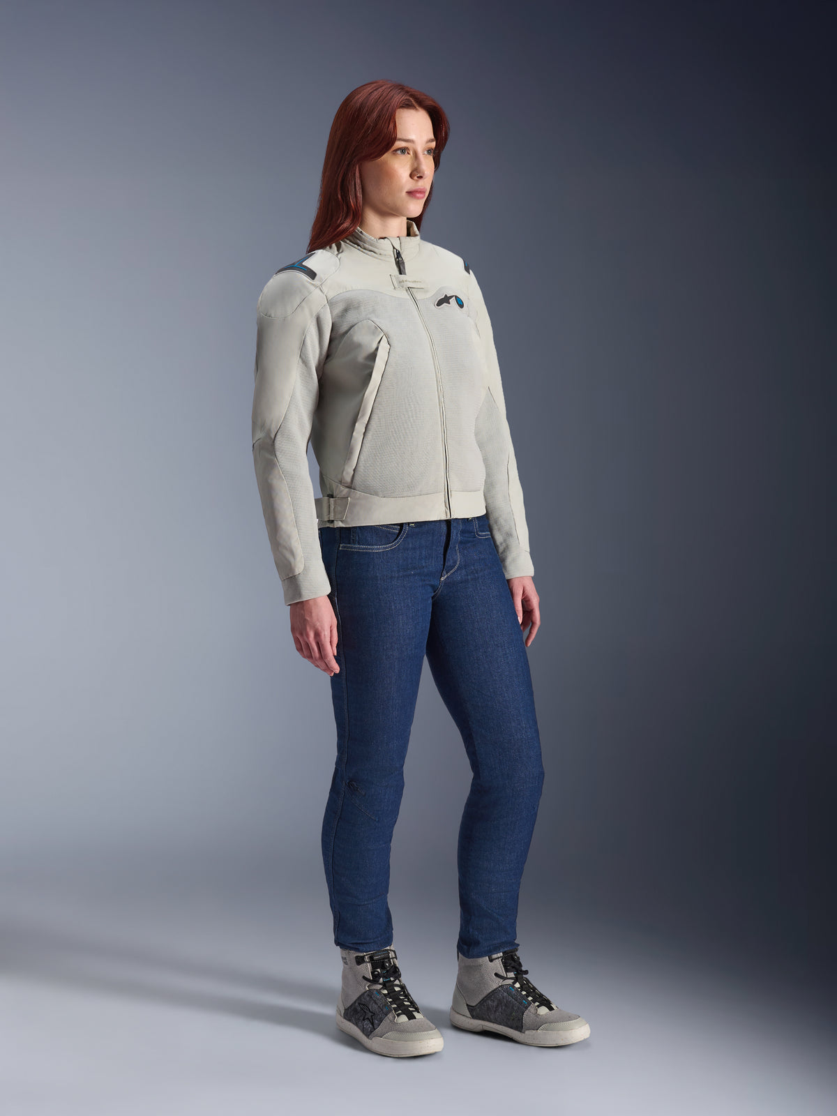 Woman wearing the Alpinestars Stella Circal-1 Air Jacket in Metal Gray and Methyl Blue, paired with blue jeans and casual riding shoes, showcasing the jacket's mesh panels and minimalist urban design.