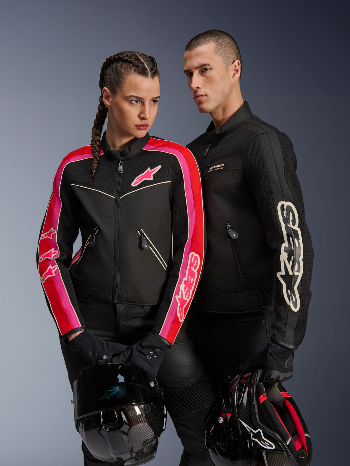 Alpinestars Stella T-Dyno Air Jacke für Damen in Schwarz, Bright Red und Fuchsia, kombiniert mit der schwarzen Dyno Air Jacke für Herren, beide Fahrer halten Motorradhelme, Studioaufnahme moderner Urban-Motorradbekleidung