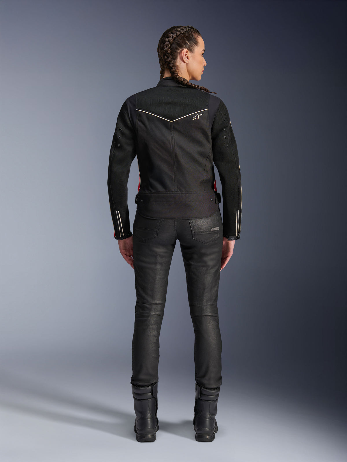 Alpinestars Stella T-Dyno Air Jacke, Rückansicht, schwarze Damen-Motorradjacke mit weißer Paspelierung und kleinem Stern-Logo, getragen mit schwarzer technischer Hose und Motorradstiefeln, schmale Biker-Passform für urbane Fahrten