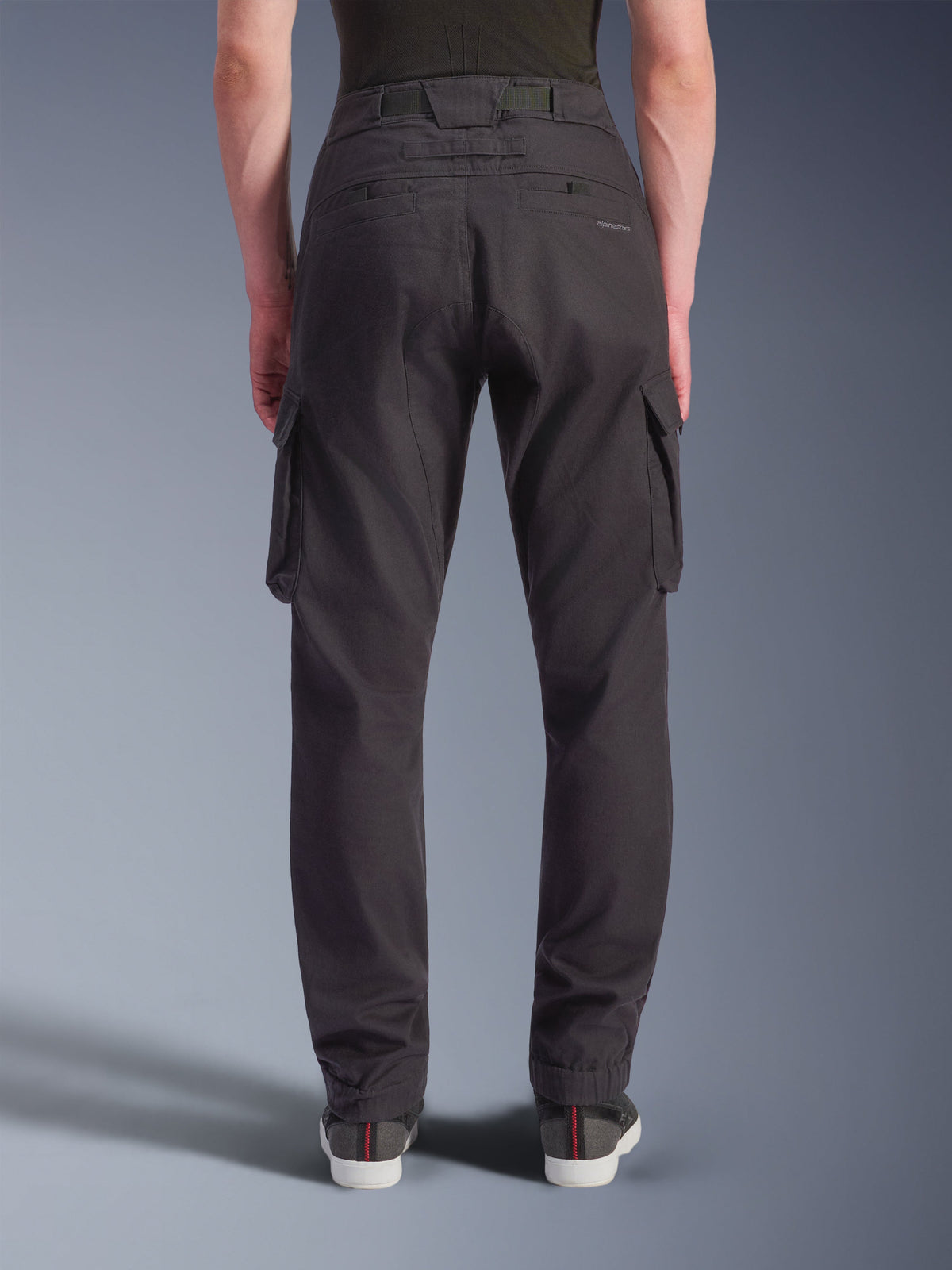 Alpinestars Flex-AST Cargo Broek - Short, stedelijke motorbroek, zwart, achteraanzicht met een regular tapered pasvorm en elastische zomen, grote cargo-zijzakken en subtiele branding op de achterzak, gedragen met casual sneakers