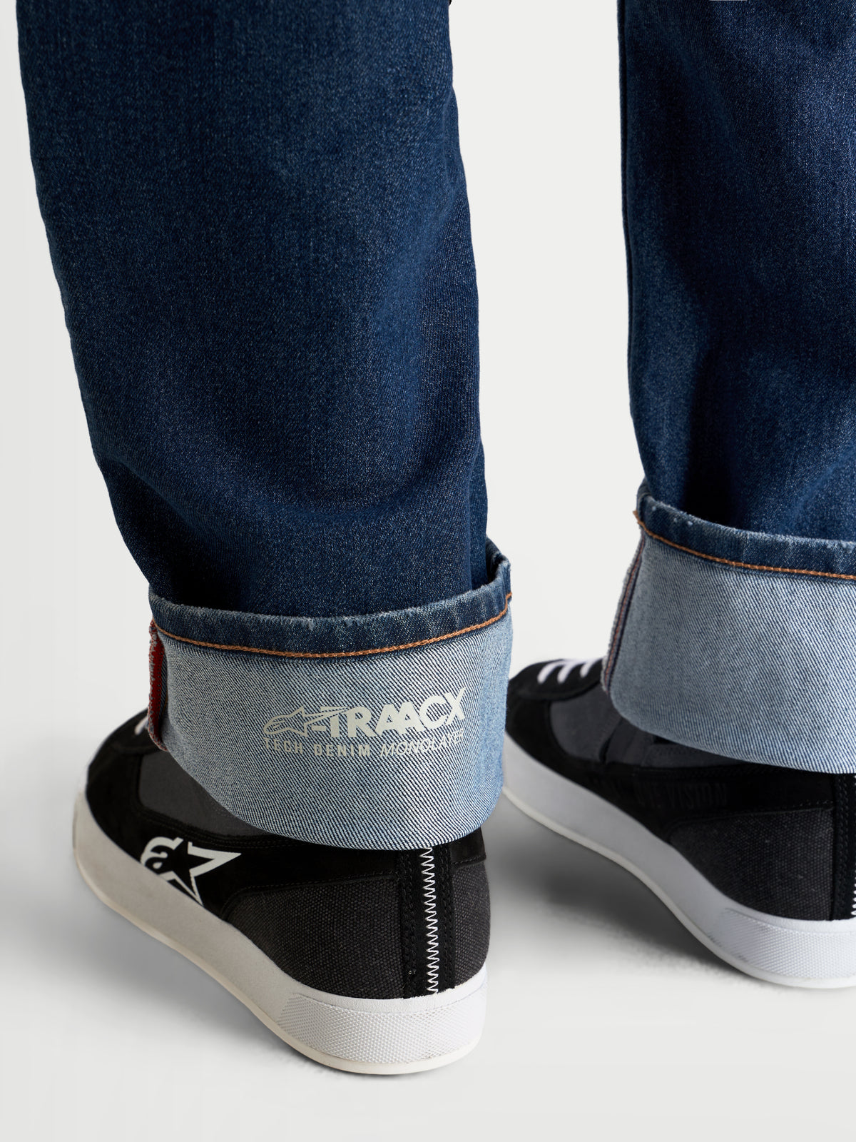 Alpinestars Flex Ast 8 Denim broek, motorjeans in middels blauw, detailopname van de omgeslagen zoom met de interne A-TRAACX enkellaags technische denim branding en selvedge-stijl randafwerking