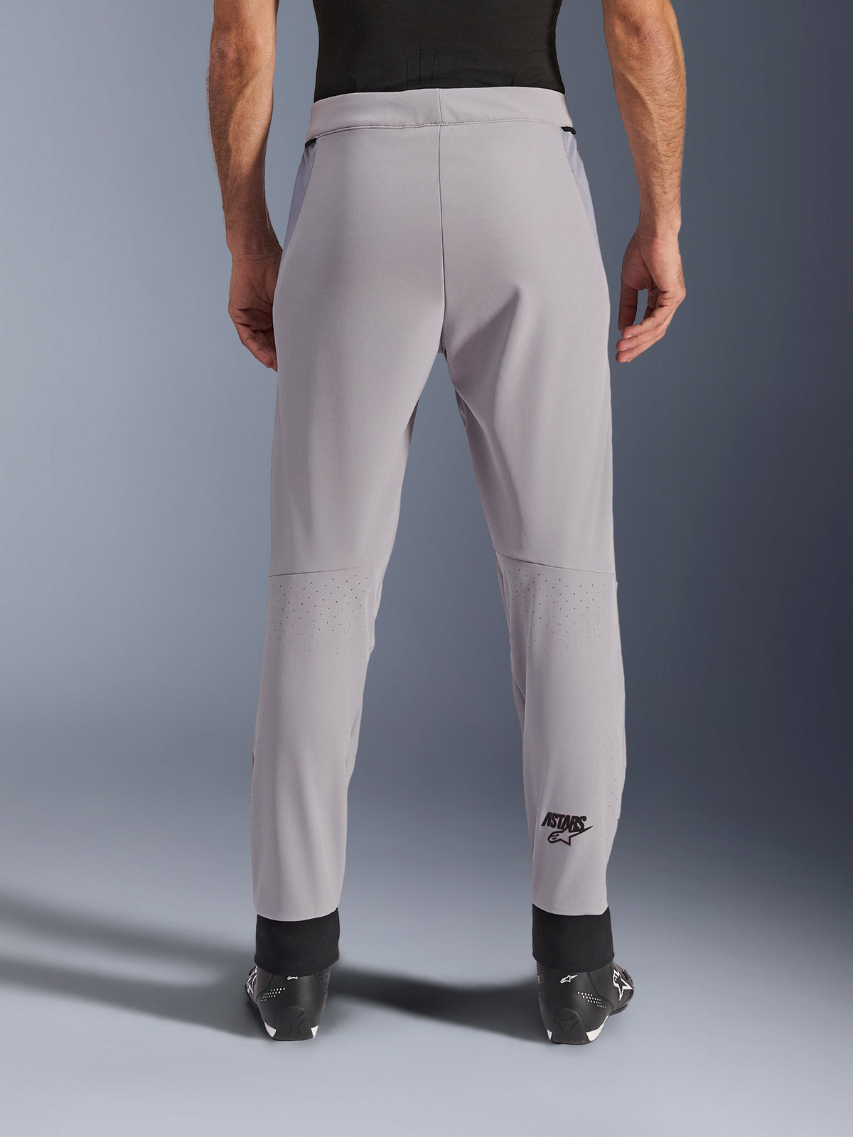 Pantalon Alpinestars Aeroshell Airflow, pantalon de moto, gris moyen, vue arrière montrant les zones perforées au laser sur les mollets et le logo Astars noir, construction en textile softshell avec poignets de cheville noirs et panneaux de hanche en maille.