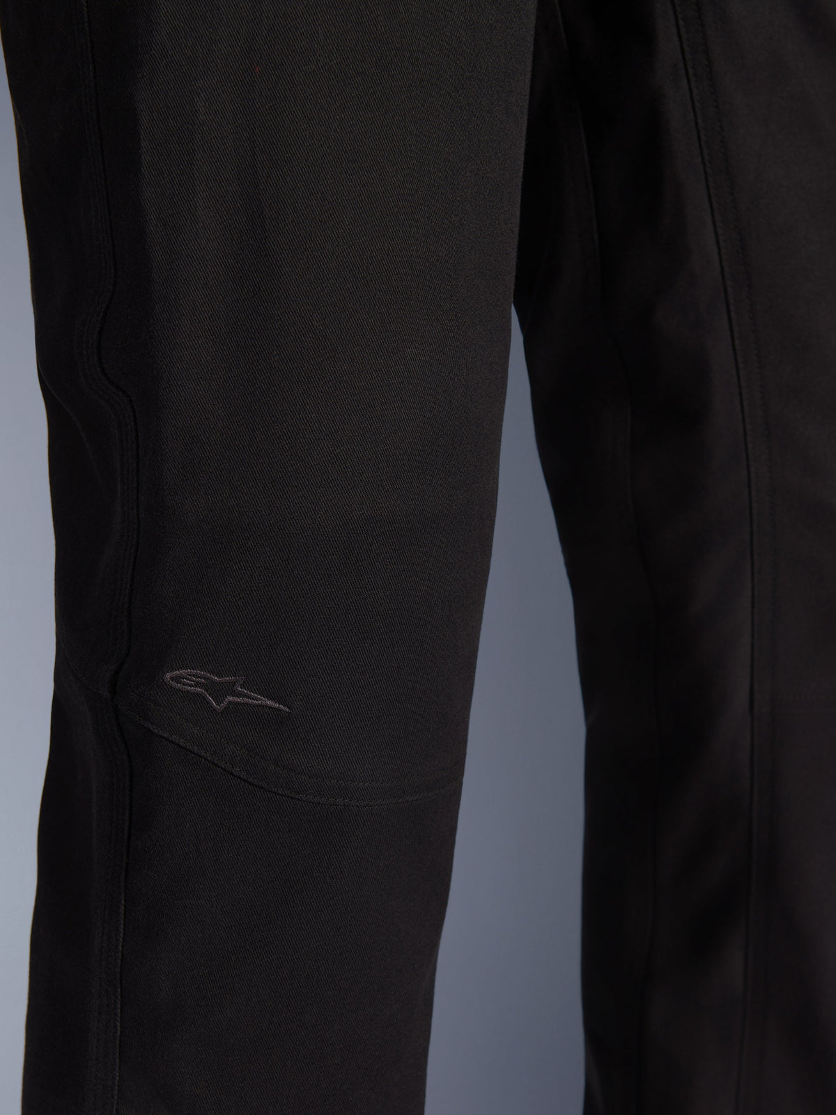 Pantalon Alpinestars Flex-AST Canvas, pantalon de moto urbain, noir, gros plan de la zone du genou avec panneaux préformés et logo brodé discret sur tissu canvas durable.