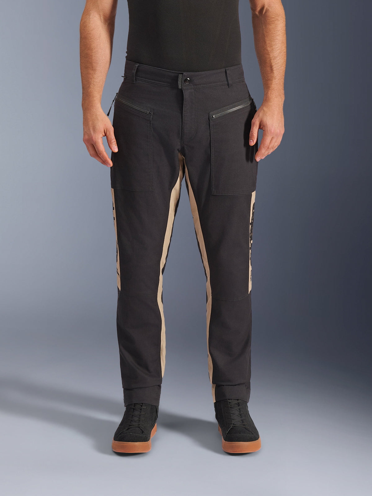 Alpinestars Flex-AST Canvas Pants, pantalon de moto urbain, noir et aluminium, design workwear d'inspiration héritage, poches avant zippées, coupe moto ergonomique, porté avec des baskets noires décontractées et un t-shirt noir, style urbain utilitaire