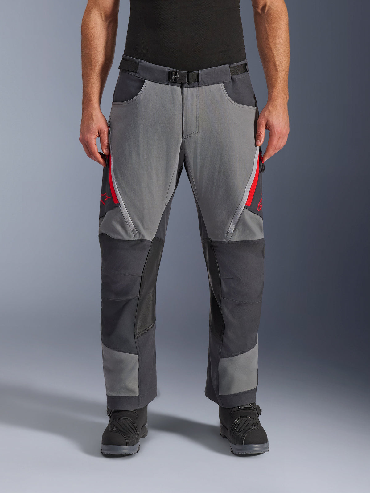 Alpinestars Maxdura Dual Pants, adventure motorbroek, donkergrijs en diepgrijs met rode accenten, vooraanzicht met dijventilatie met rits, magnetische gespsluiting en verstevigde kniepanelen, over-de-laars ontwerp voor dual-sport rijden.