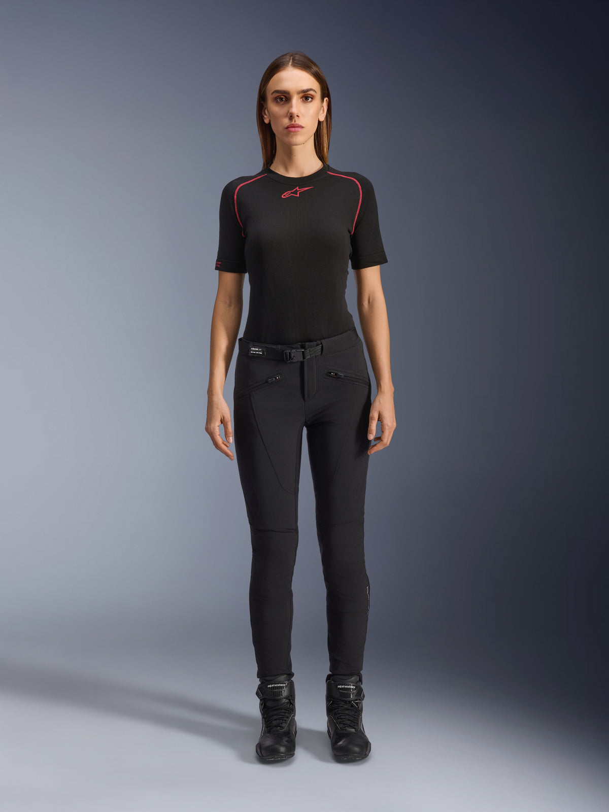 Alpinestars Alamosa Damenhose, schmal geschnittene schwarze Motorradhose, an einem Modell in der Vorderansicht gezeigt, mit Reißverschlusstaschen vorne und integriertem Taillengürtel, minimalistischer, von Streetwear inspirierter Stil für urbanes Fahren