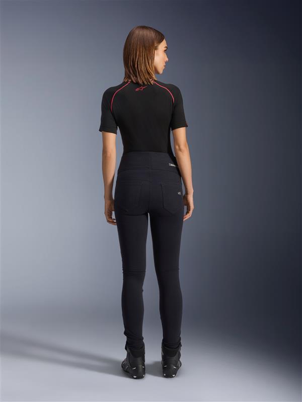 Alpinestars Stella Flex-Ast Leggings, motorleggings voor dames, zwart, achteraanzicht toont de hoge taille en slanke pasvorm, gedragen met zwarte top met korte mouwen en zwarte motorlaarzen, urban motorkleding