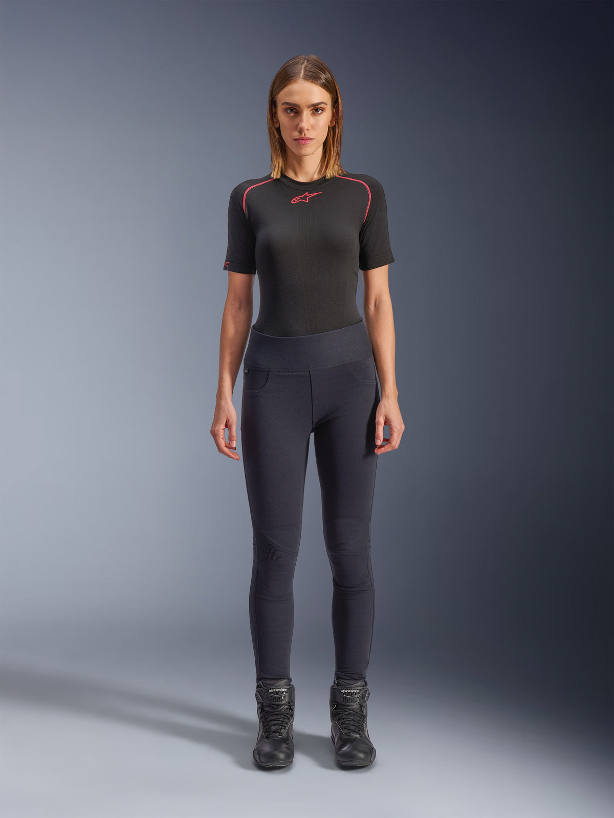 Alpinestars Stella Flex-Ast Leggings, dames motorlegging, zwart, gedragen met een zwarte top met korte mouwen met rode details en zwarte motorlaarzen, slim-fit eigentijdse urban motorkleding, vooraanzicht