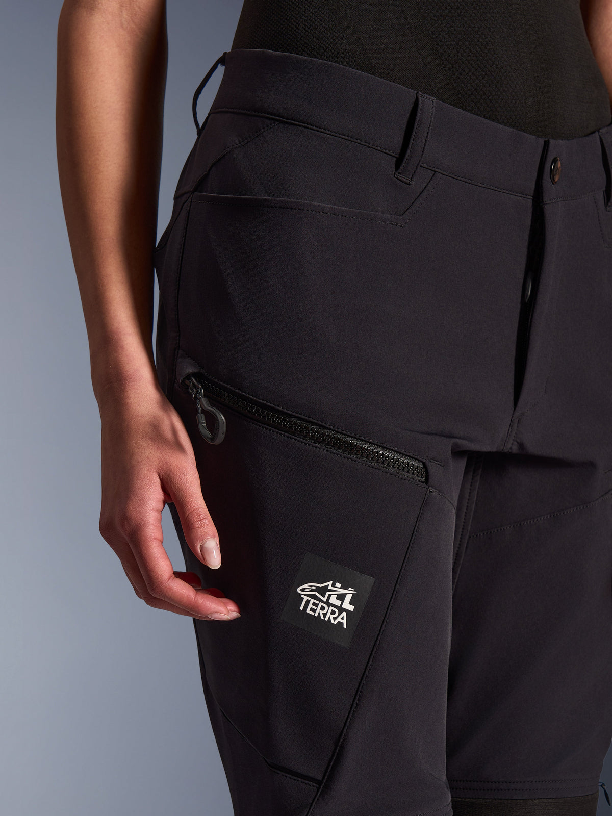 Alpinestars Stella Flex-AST Explorer damesmotorbroek, zwart, close-up weergave van de dijbeenzak met ritssluiting en ALL TERRA merkpatch, lichtgewicht stretchtextiel voor adventure motorrijden