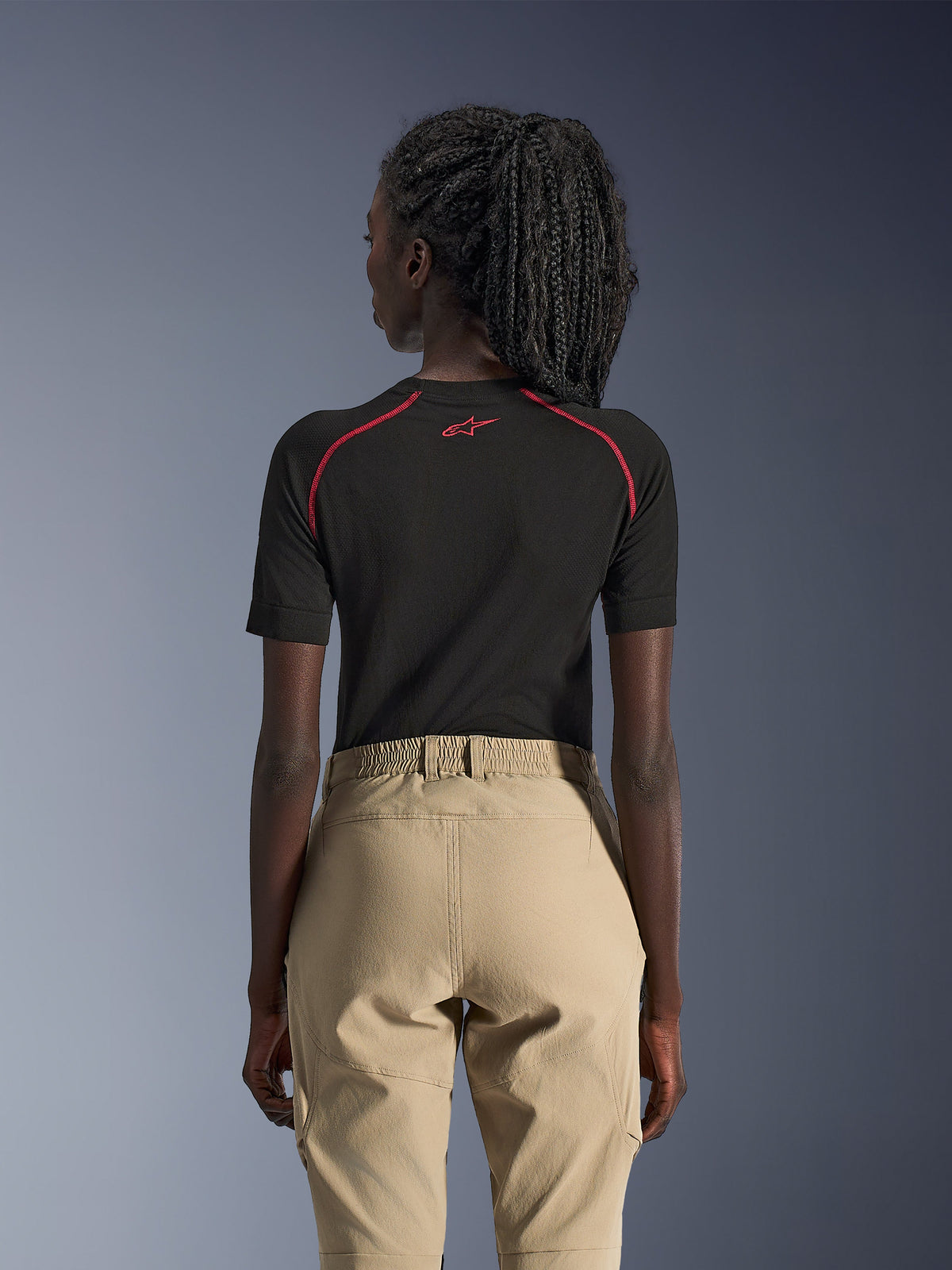 Alpinestars Stella Flex-AST Explorer damesmotorbroek, zand, adventure motorbroek, achteraanzicht gedragen met een zwarte basislaag met korte mouwen en rode accenten, voorzien van een elastische tailleband en duurzame textielconstructie