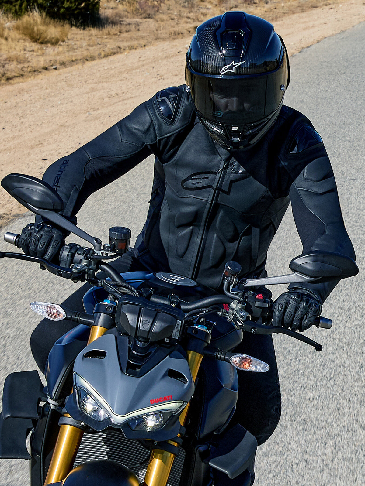 Alpinestars Dusk Lederjacke, schwarze Herren-Road-Racing-Lederjacke aus Leder mit Schulterschutz, auf einer grauen Ducati.