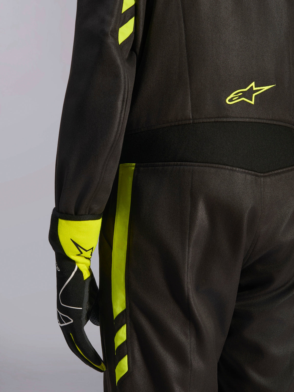 Alpinestars GP Race V3 Anzug FIA, Schwarz und Gelb Fluo, Nahaufnahme der Taille und des seitlichen Beins, mit Aramid-Stretcheinsätzen und passendem Rennhandschuh, professionelle Autorennsport-Ausrüstung