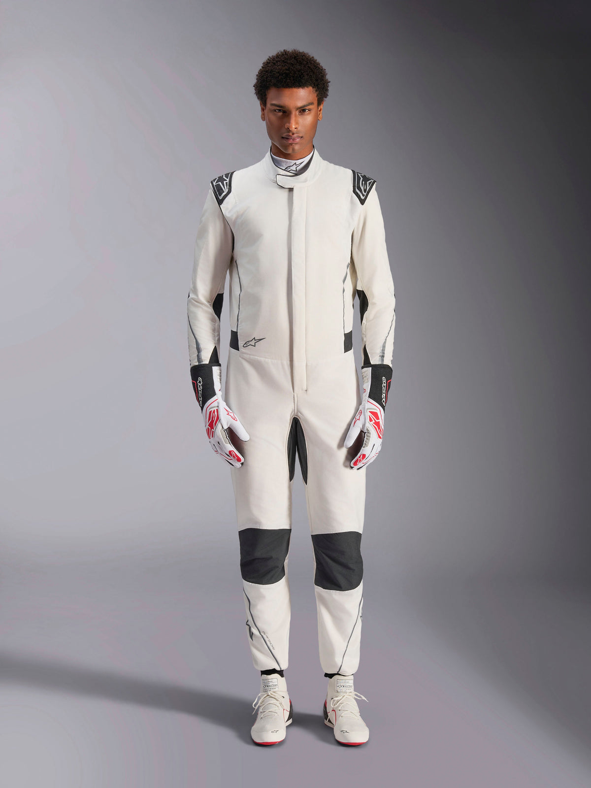 Alpinestars Hypertech V3 Suit, professioneel autoracepak, wit, zwart en zilver, gedragen door model met rood-witte handschoenen en bijpassende witte raceschoenen, voorzien van zwarte contrastpanelen en Alpinestars-logo's, atletisch slim-fit ontwerp