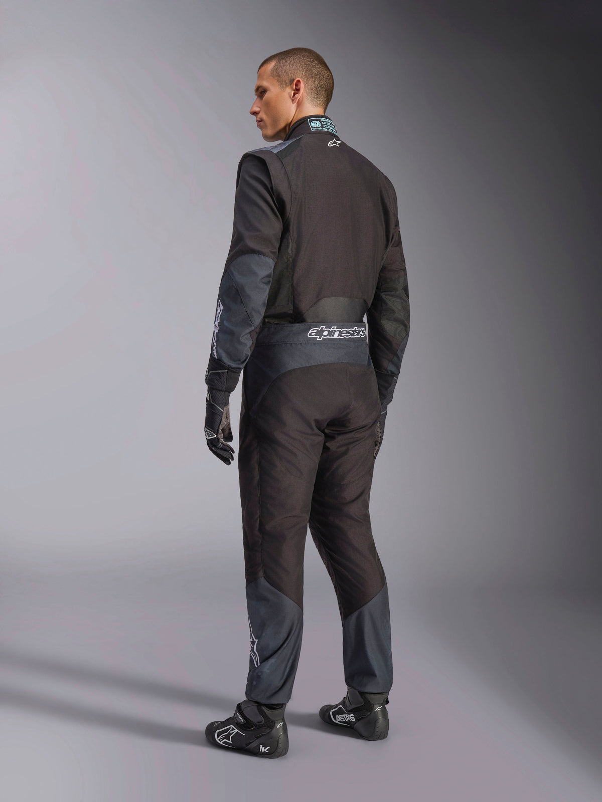 Combinaison Alpinestars KMX-5 V3 en Black Dark Shadow, vue de dos d'un mannequin portant un équipement de karting complet avec gants et chaussures assortis, marquage Alpinestars à la taille et accents gris foncé, équipement de karting professionnel