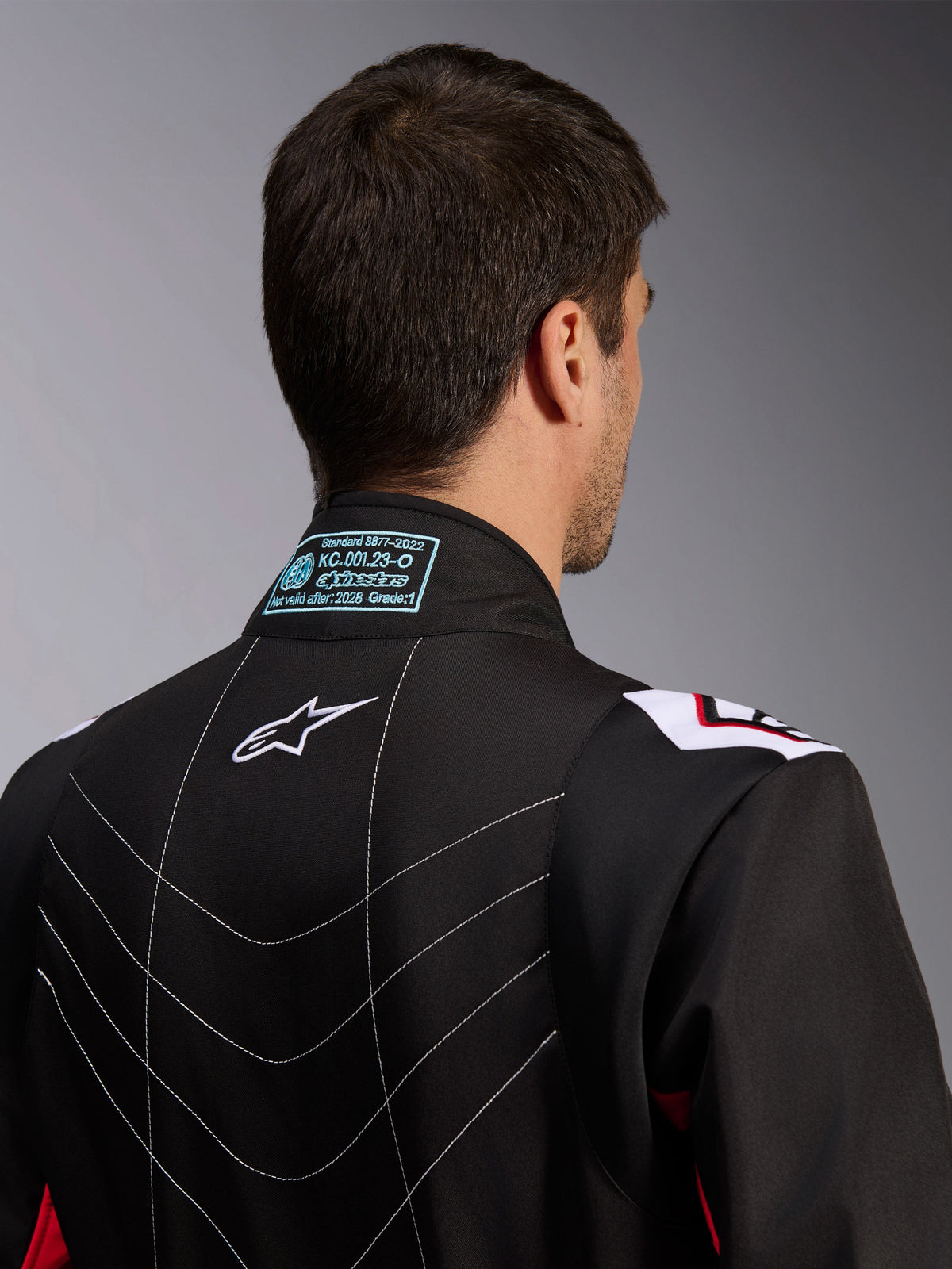 Alpinestars KMX-9 V3 Pak, kartingpak, zwart rood wit, achteraanzicht van de kraag met FIA 8877-2022 homologatielabel, wit Astars-logo en decoratieve stiksels