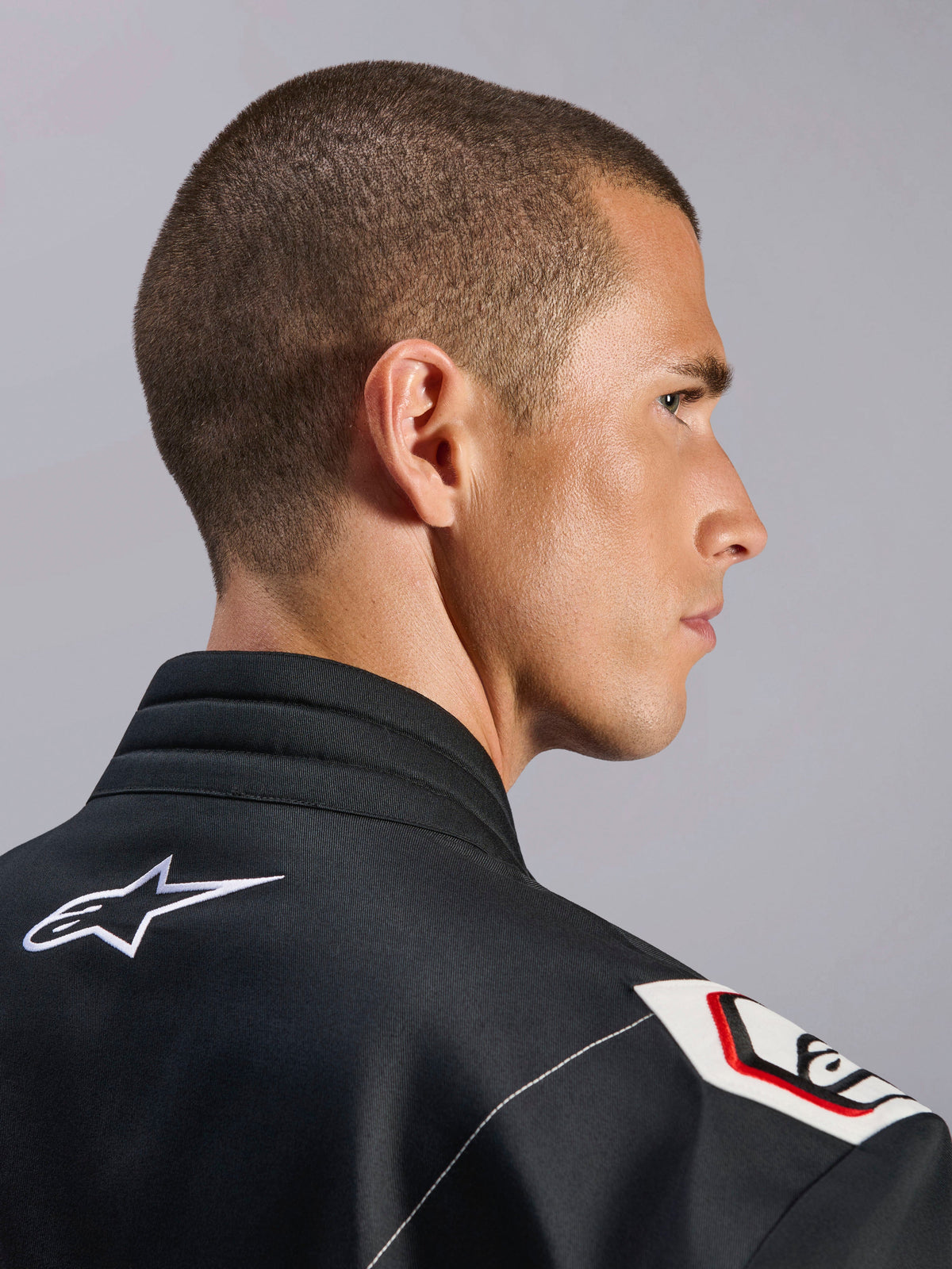 Combinaison Alpinestars Kart Indoor V2, noire, vue rapprochée du col ergonomique et du design d'épaule dérivé de la Formule 1, avec logo Alpinestars blanc et détails inspirés de la course sur tissu sergé durable