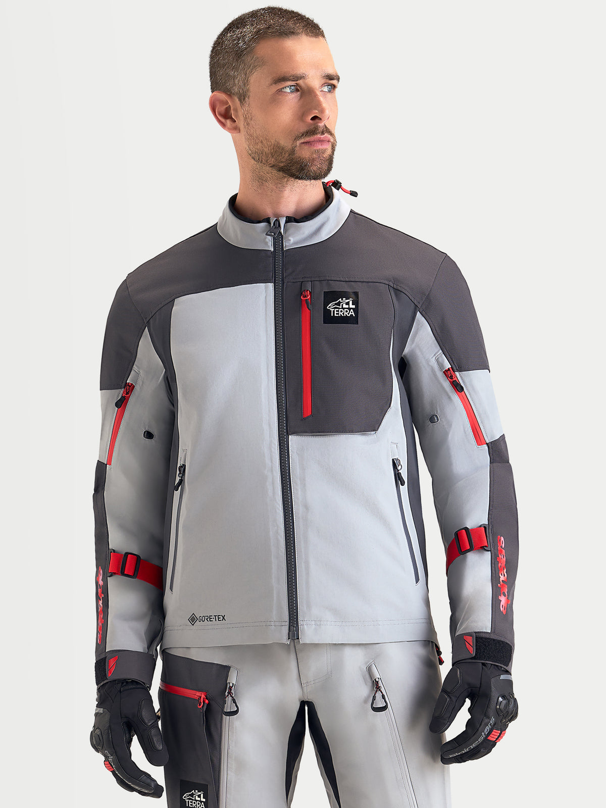 Alpinestars Arenis Gore-Tex jas, heren adventure motorjas in middengrijs, donkergrijs en zwart, vooraanzicht gedragen door een model met waterdichte textielconstructie en borstzak met rits