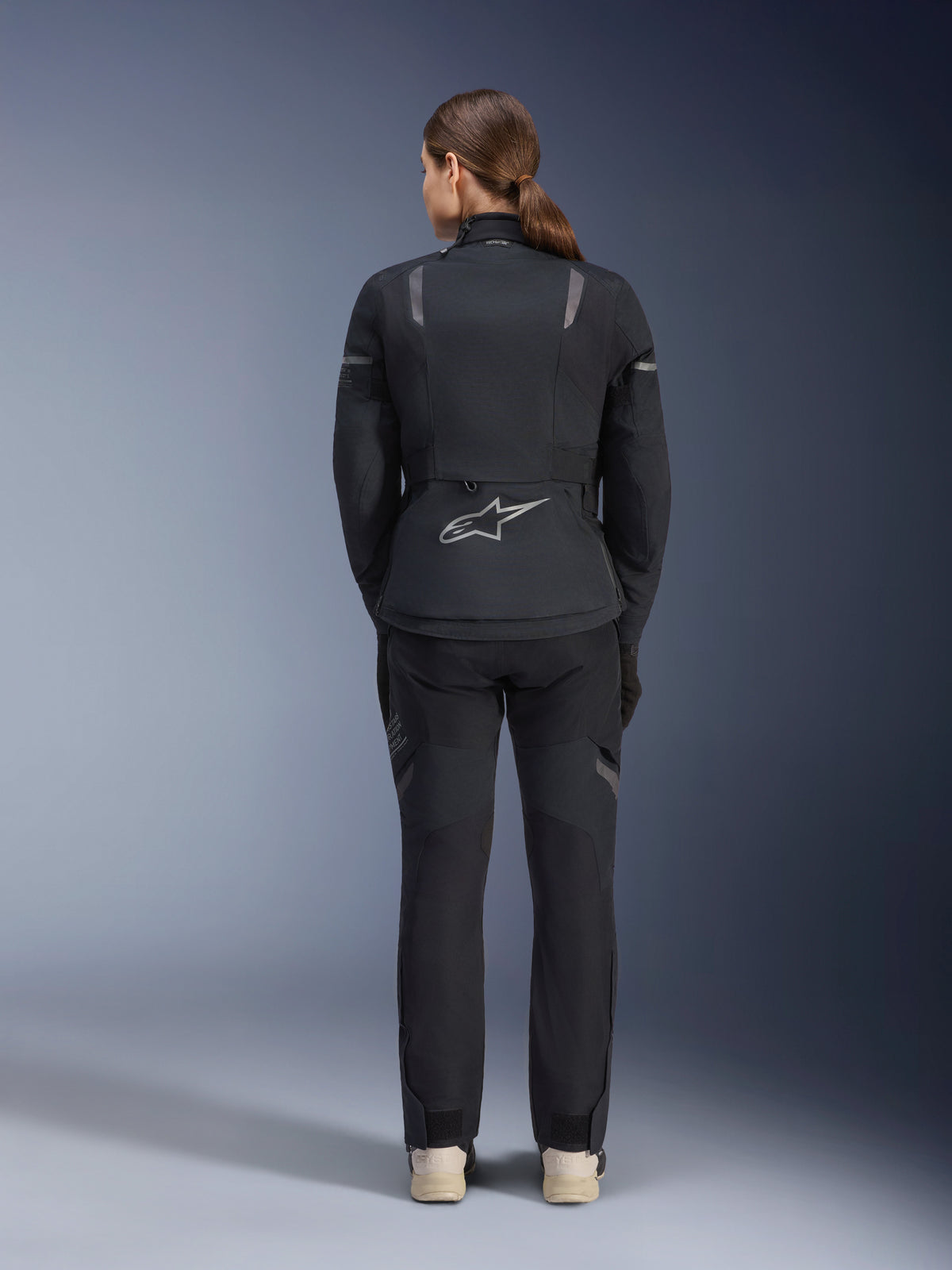 Ensemble veste et pantalon Alpinestars Stella ST-7 2L GORE-TEX, tenue de moto Adventure Touring pour femme, noir et gris foncé, vue de dos montrant le logo Astar et des détails réfléchissants, construction textile imperméable et durable