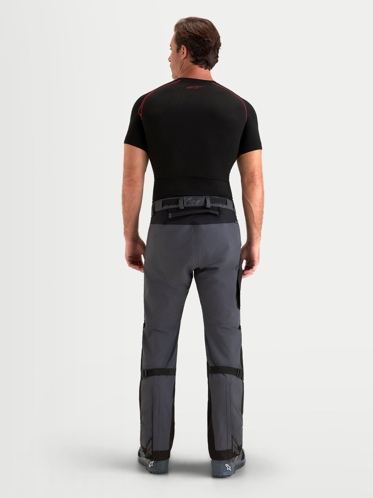 Alpinestars Arenis Gore-Tex Pantalons, pantalon de moto adventure pour homme noir et gris foncé, vue de dos sur un modèle montrant la construction textile imperméable et la fermeture à la taille