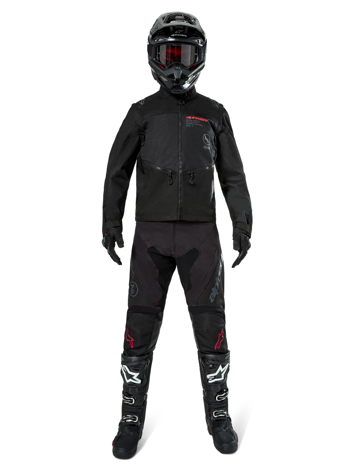 Veste Alpinestars Pro-Dura, veste d'enduro tout-terrain noire, présentée sur un modèle avec un équipement complet comprenant un casque noir avec des lunettes rouges, un pantalon noir avec des accents rouges, des bottes noires et blanches et des gants noirs, design robuste inspiré du rallye pour la conduite sur sentier
