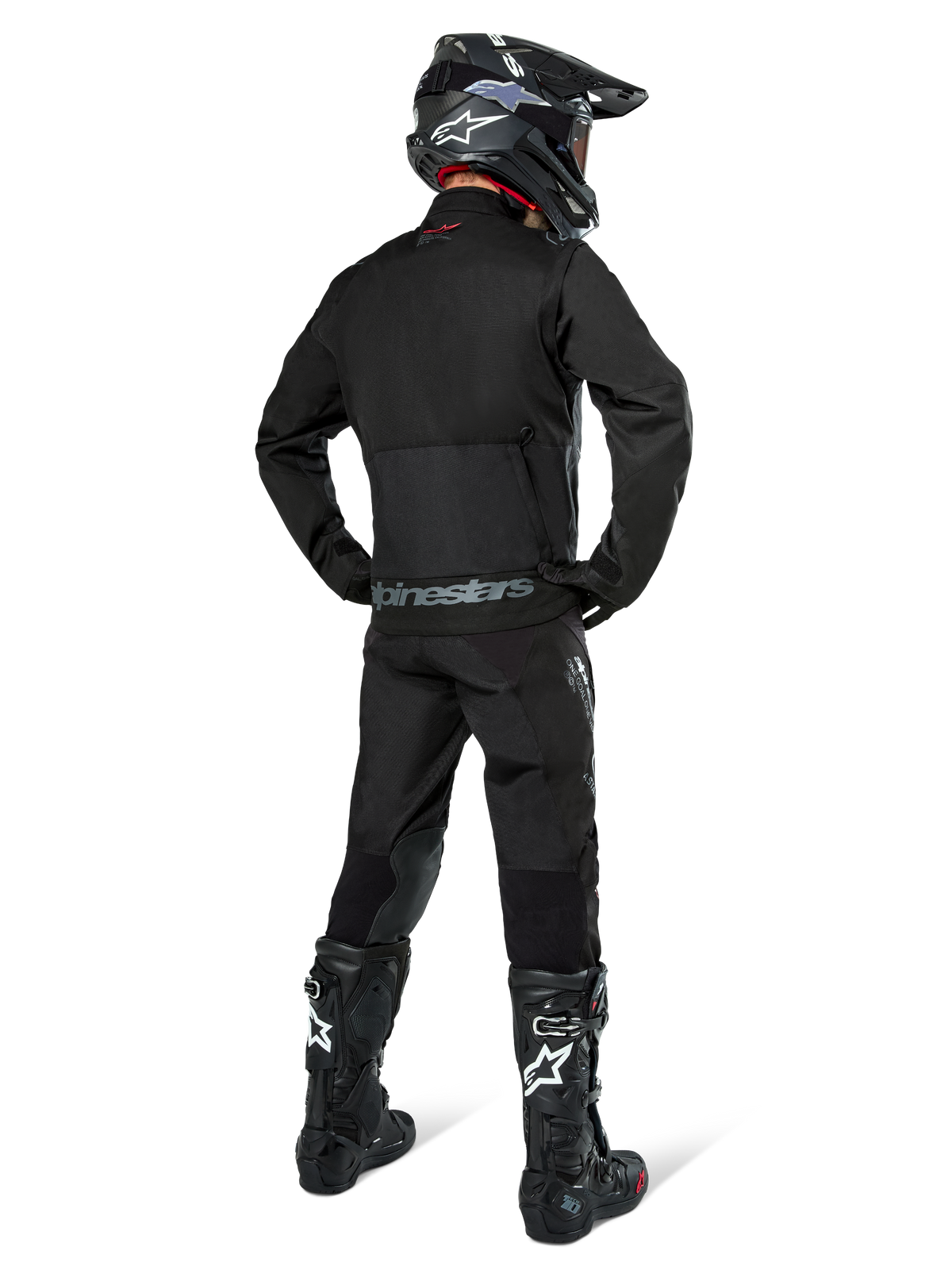 Veste Alpinestars Pro-Dura, veste d'enduro tout-terrain noire, vue arrière portée avec le pantalon assorti et des bottes Tech 10 noires, logo Alpinestars distinctif dans le bas du dos, construction en textile robuste pour une conduite agressive sur sentier