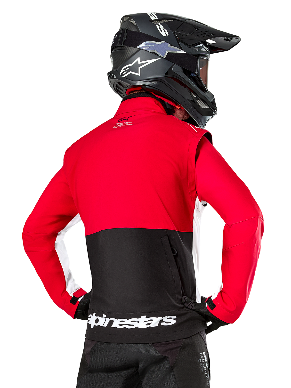 Alpinestars Lite-Dura Softshell-Jacke, Schwarz Hellrot Weiß, Rückansicht an einem Motocross-Fahrer, roter Oberkörper und Ärmel mit schwarzem Einsatz am unteren Rücken, Rückentasche mit Reißverschluss, weißes Alpinestars-Logo am Saum, getragen mit schwarzem Helm und Hose