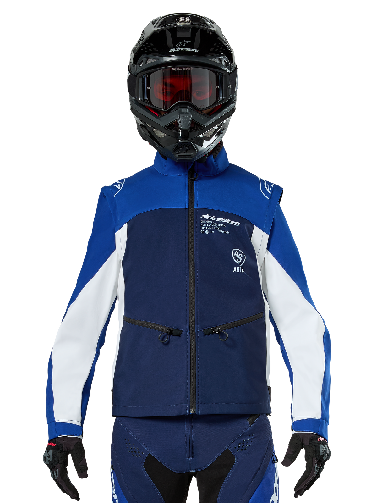 Motocross-Fahrer in der Alpinestars Lite-Dura Softshell-Jacke in Navy, Hellblau und Weiß, Frontansicht, kombiniert mit einem schwarzen Helm und rot getönter Brille, technisches winddichtes Design mit Reißverschlusstaschen und weißen Akzenten für Offroad-Enduro-Fahrten