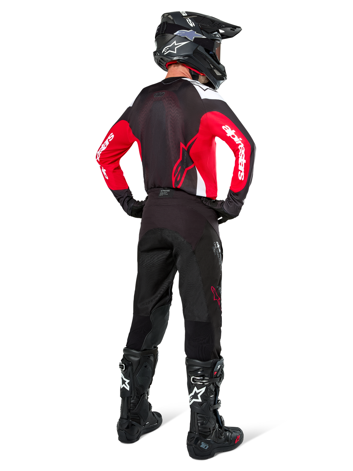 Pilote de motocross vu de dos portant le pantalon Alpinestars Pro-Dura en Black Magnet White, associé à un maillot rouge et noir et des bottes noires, ensemble d'équipement tout-terrain coordonné pour l'enduro