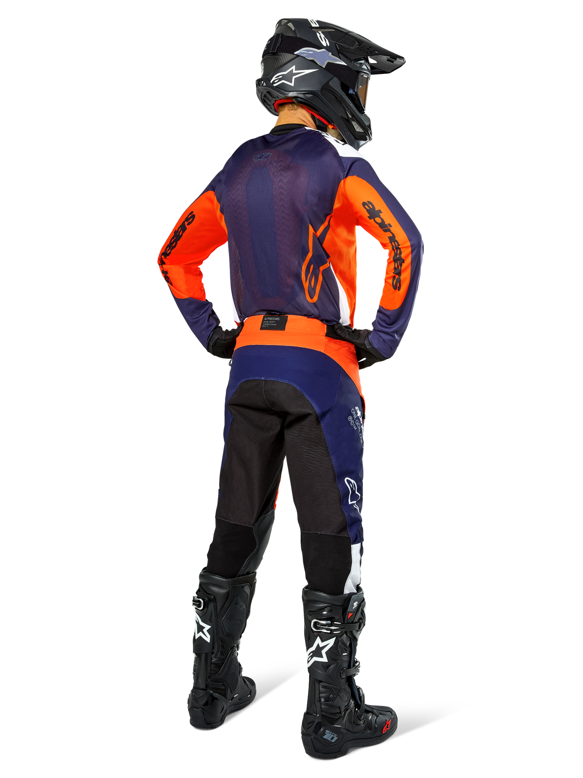 Pilote de motocross de dos portant une tenue de course complète Alpinestars, maillot bleu navy et orange, pantalon Pro-Dura en Navy Hot Orange White, casque noir et bottes noires, ensemble professionnel de course tout-terrain