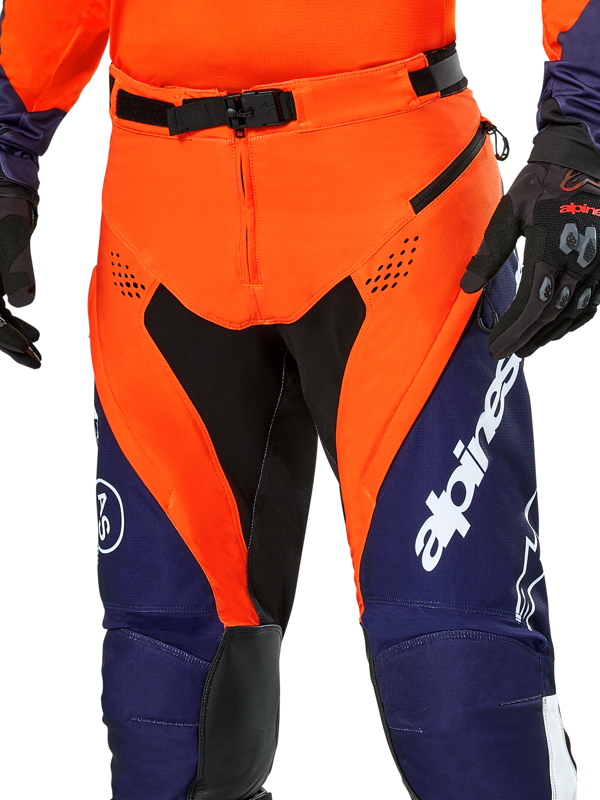 Pantalon Alpinestars Pro-Dura, pantalon de moto enduro, bleu marine, orange vif et blanc, vue détaillée de la taille avec boucle magnétique SX2 et ouvertures d'aération zippées sur les cuisses, matériau ripstop durable avec marquage distinctif, porté avec l'équipement assorti