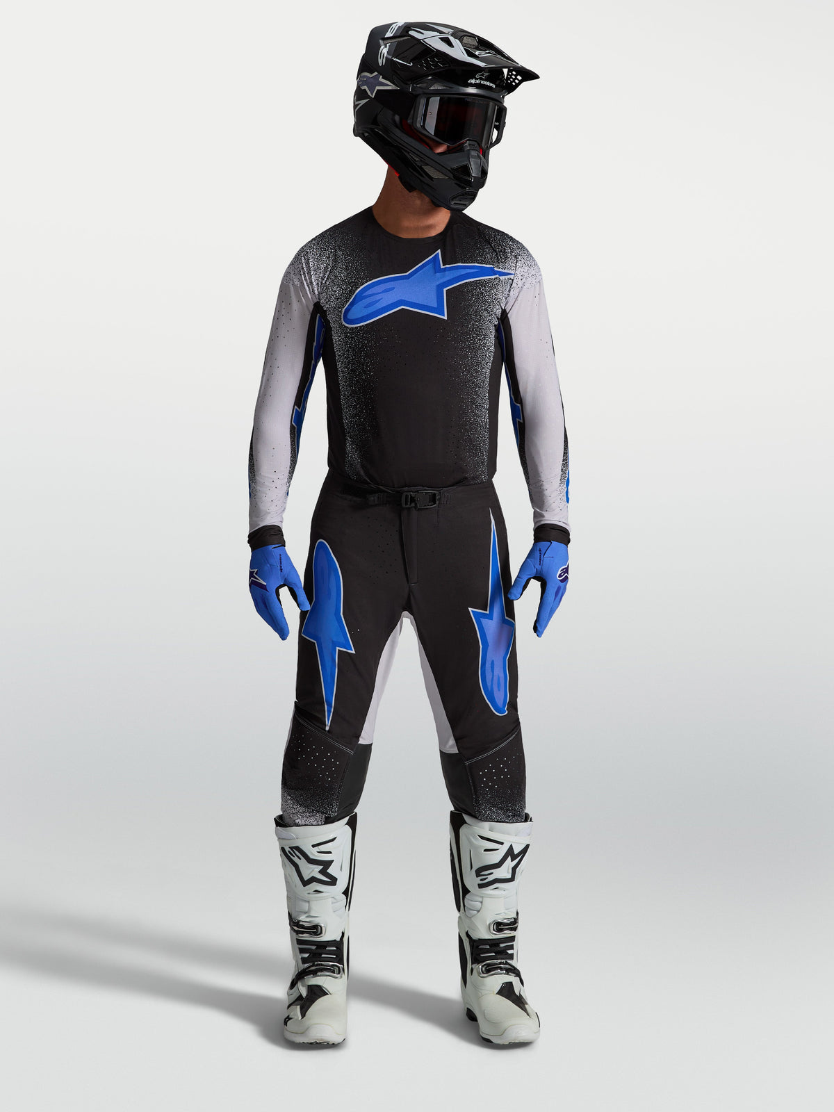 Alpinestars Supertech Hiten AFD broek, zwarte en blauwe motocrossbroek op model met bijpassende jersey en witte motorlaarzen.