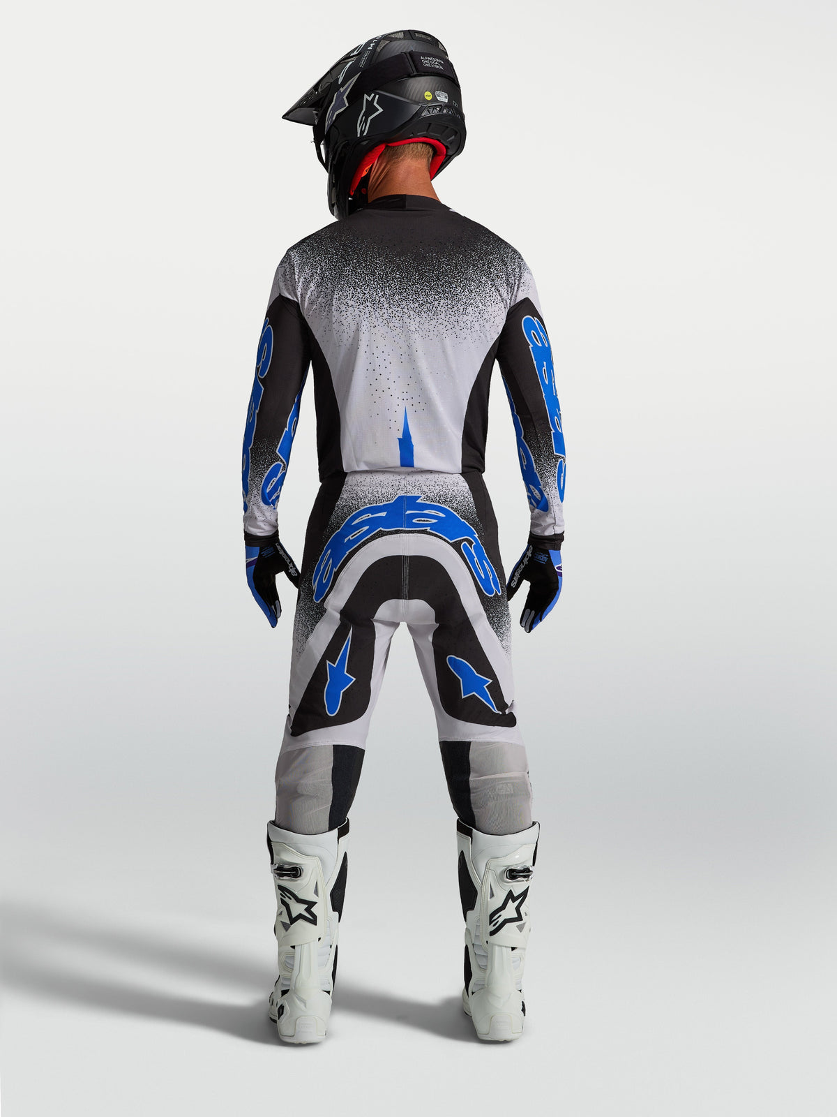 Alpinestars Supertech Hiten AFD broek, heren motocrossbroek in blauw en wit, atletisch achteraanzicht in race-outfit.