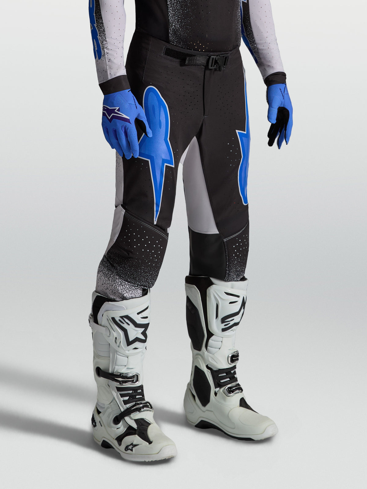 Alpinestars Supertech Hiten AFD broek, heren motorcrossbroek in zwart en blauw met een atletische pasvorm en witte laarzen.